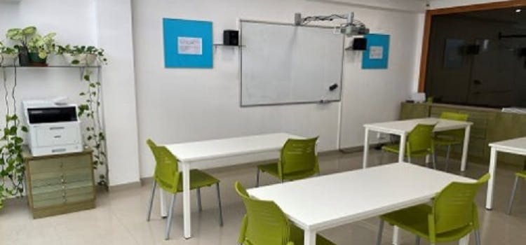Salón de clases de Dublins english room con pizarra mesas blancas y sillas verdes.