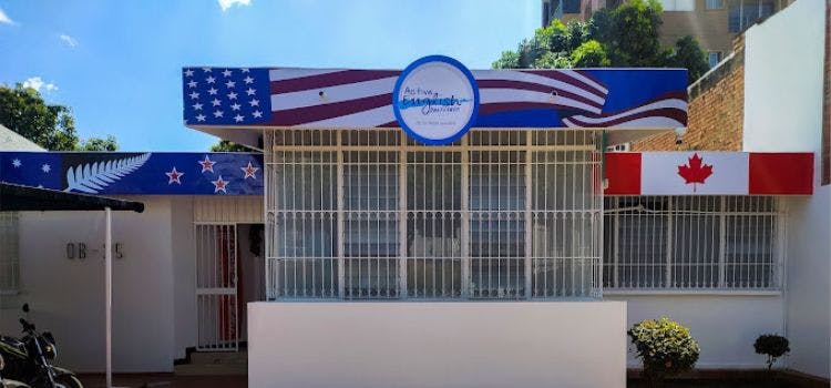 Fachada de Active English Institute con muchas ventanas y banderas de estados unidos y cadana