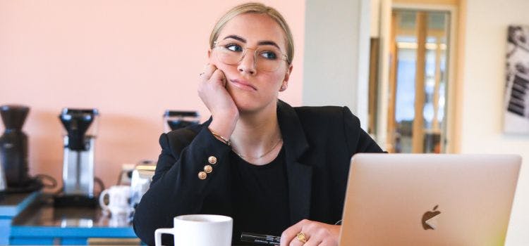 Persona frente a un computadora con cara de aburrimiento