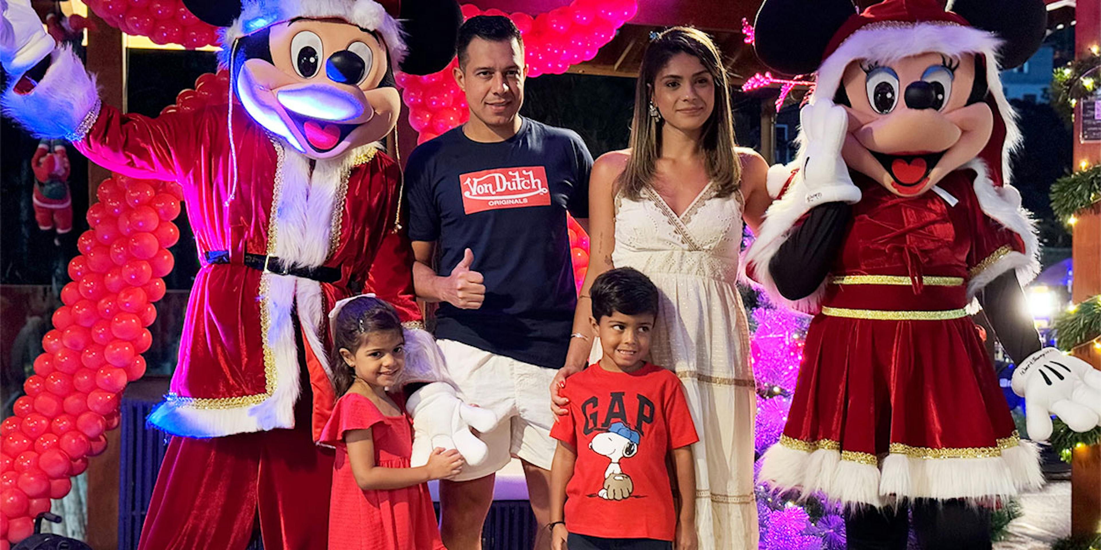 família posando pra foto com mickey e minnie natalinos