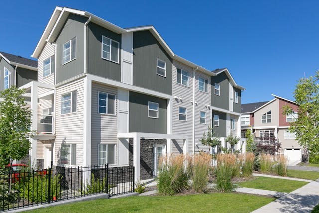White and grey townhome building with garden out front