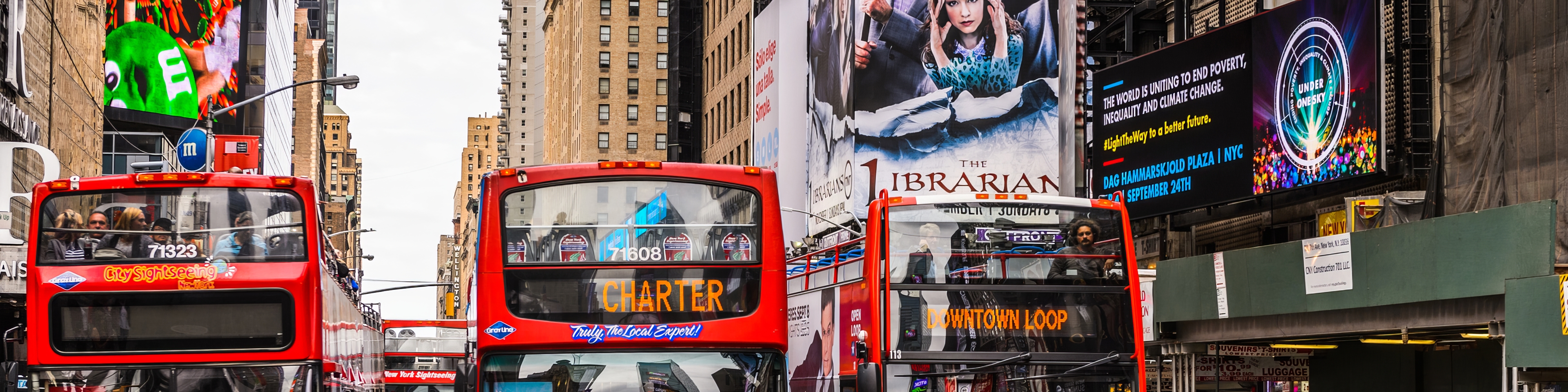 Multiple red double-decker sightseeing buses in a busy urban area, illustrating a high-traffic environment for transit fleet coordination and dispatch.