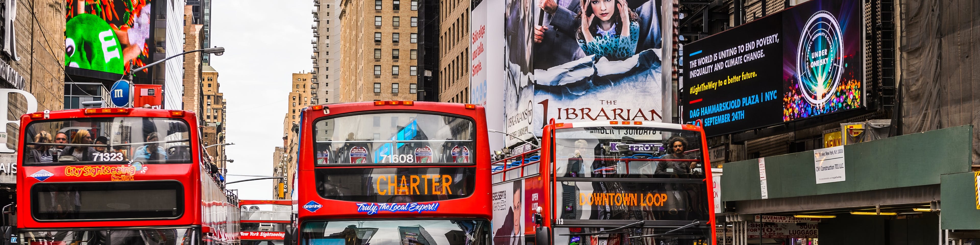 Multiple red double-decker sightseeing buses in a busy urban area, illustrating a high-traffic environment for transit fleet coordination and dispatch.