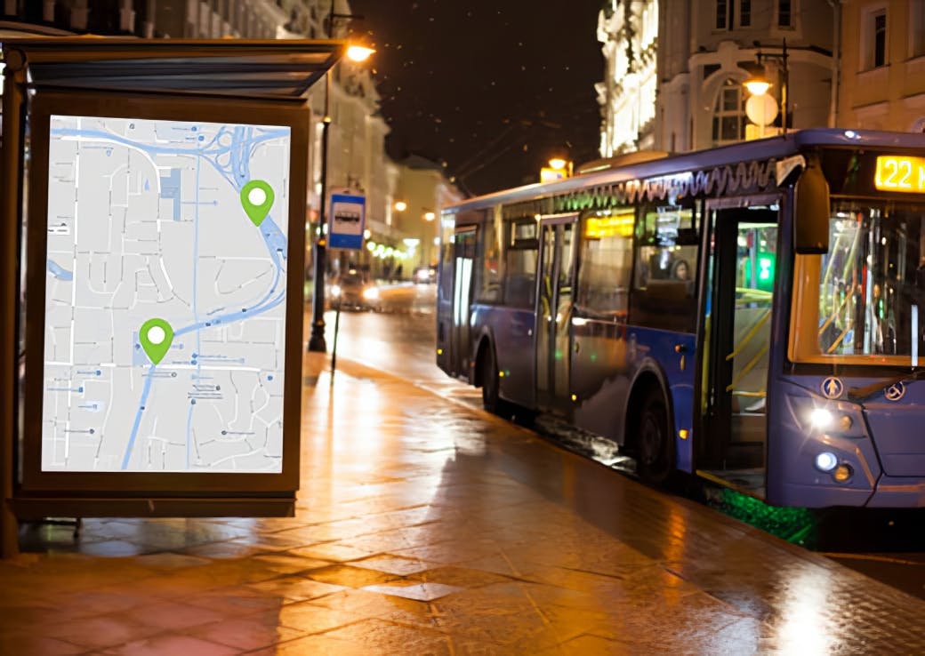 Digital transit display at a bus stop showing a live map with route markers, next to a city bus at night, illustrating real-time public transportation route updates.