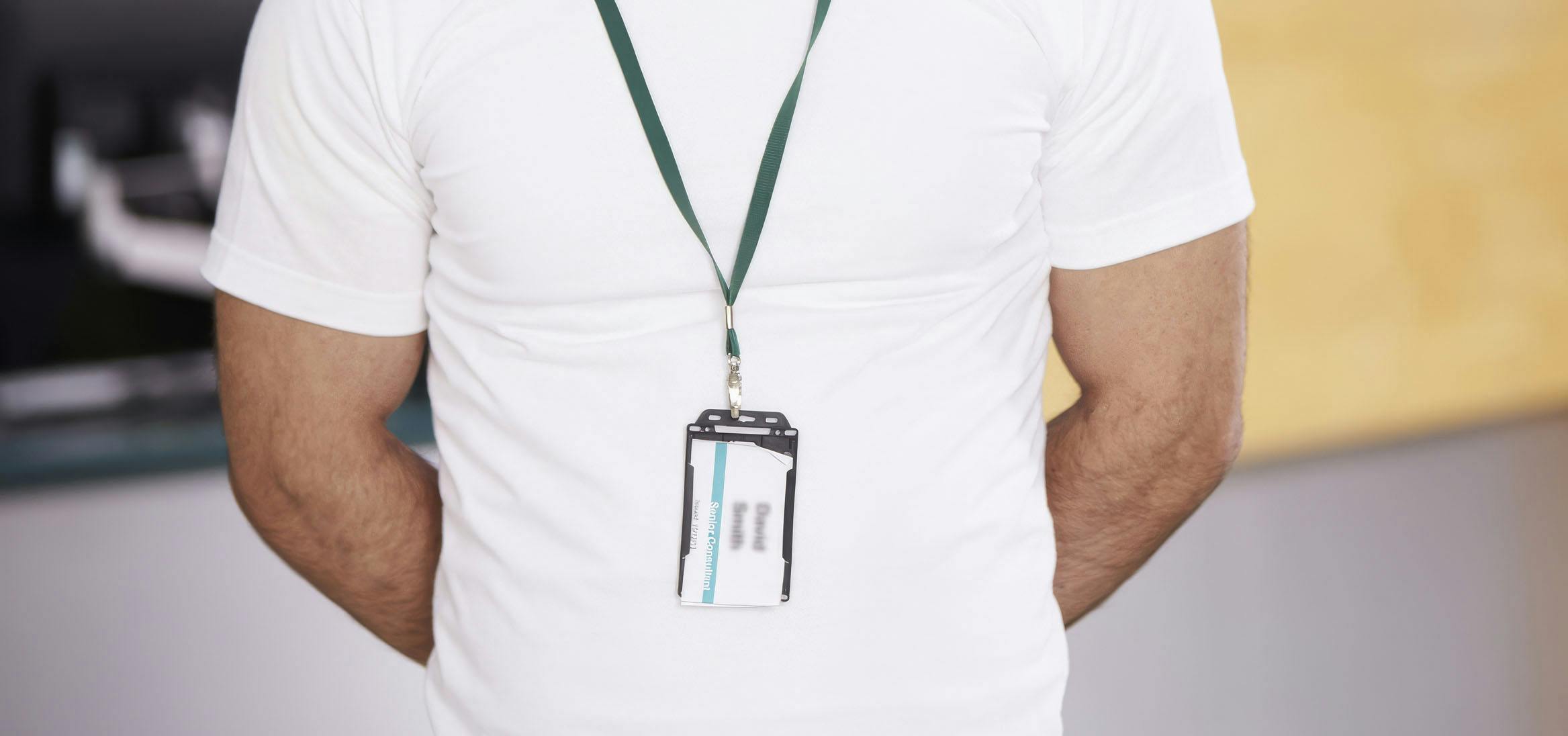 Close-up of a person wearing a white shirt and a lanyard with an ID card, representing student or employee identification used for authorized access in a transit system.