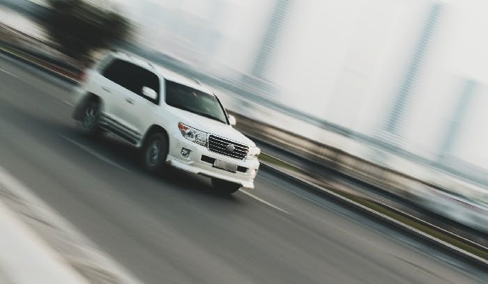 a photograph of a car with motion blurred background suggesting that the car is travelling at high speeds