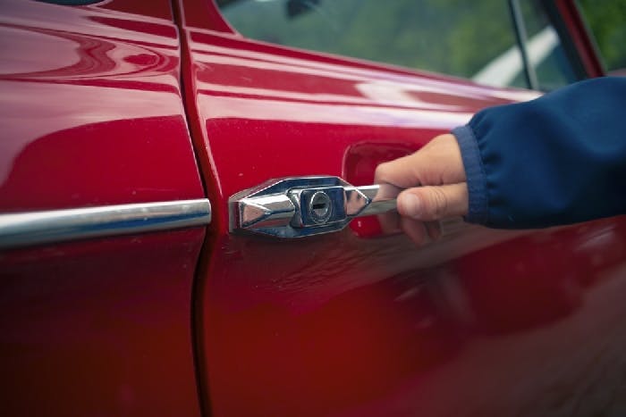 photograph of a person's hand opening a car door