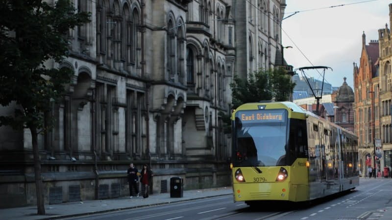 A tram driving through Manchester city centre
