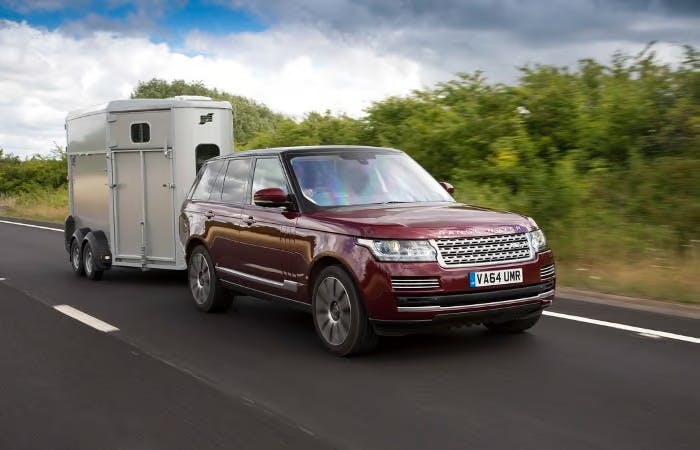 Range rover towing trailer on empty road