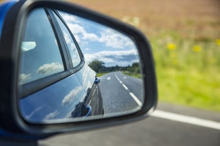  Blue car side mirror reflecting empty road