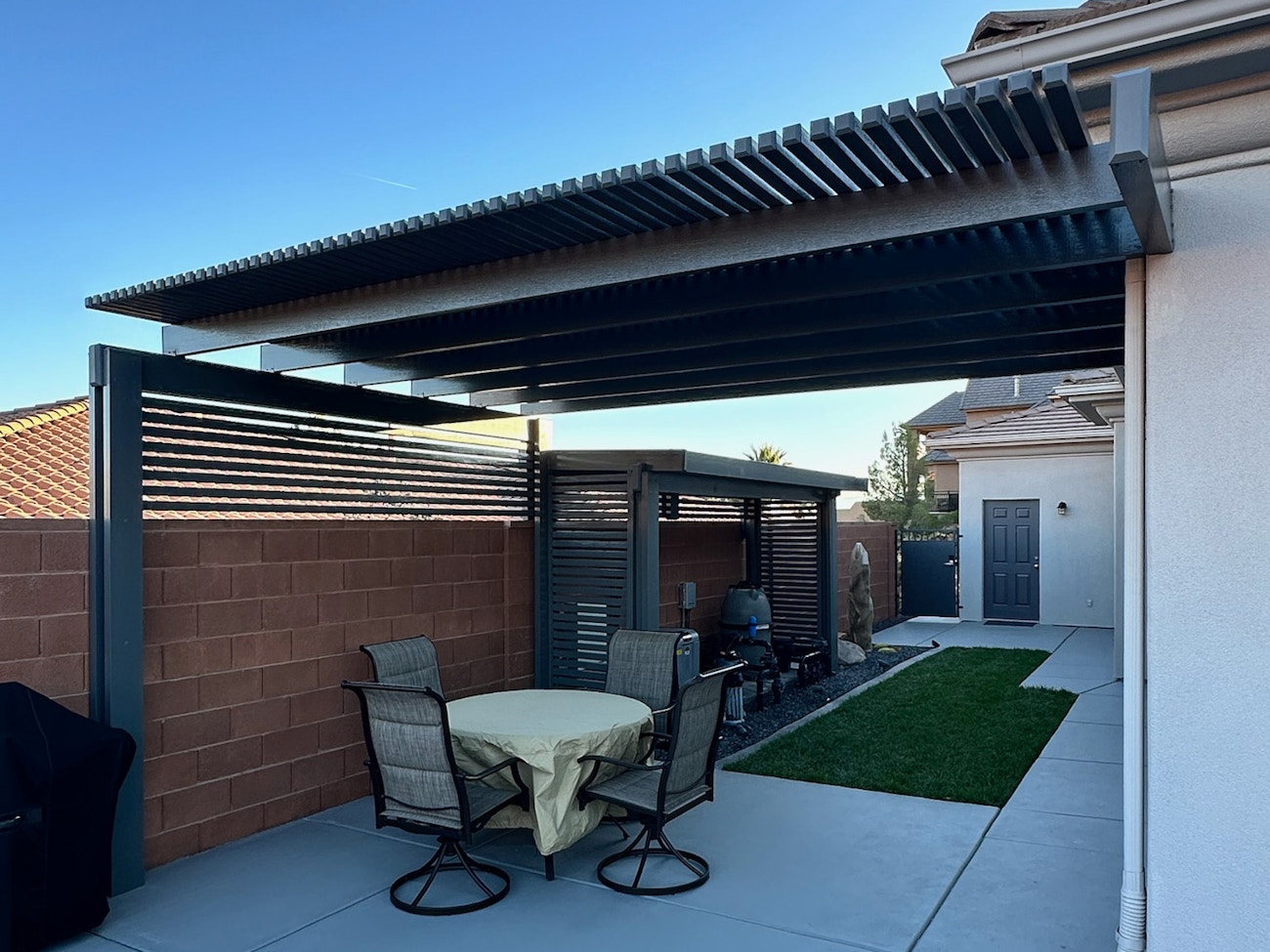 Aluminum lattice awning in slate gray with privacy wall protecting patio furniture in Washington, Utah