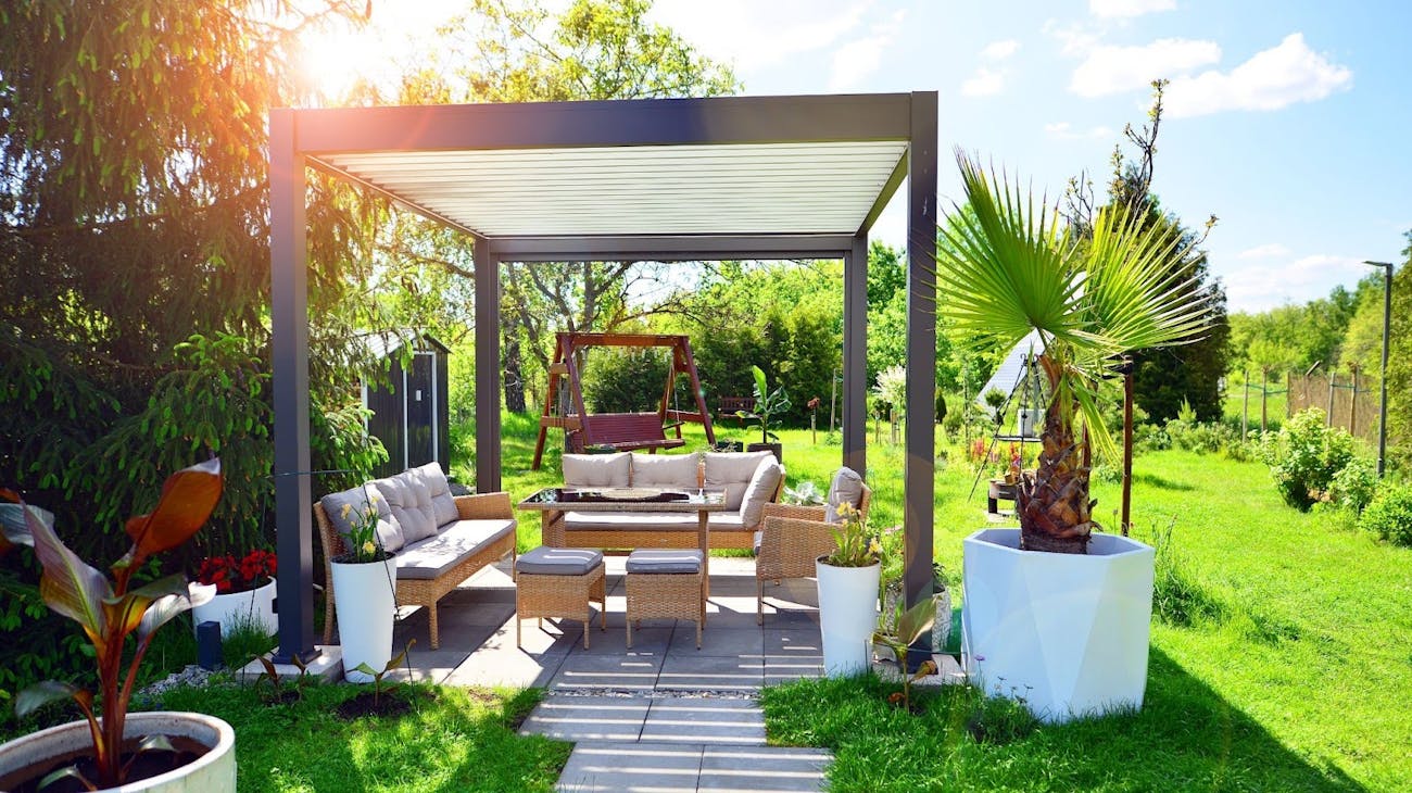 Modern aluminum patio cover ideas over an outdoor seating area surrounded by greenery, illustrating stylish and comfortable backyard design.