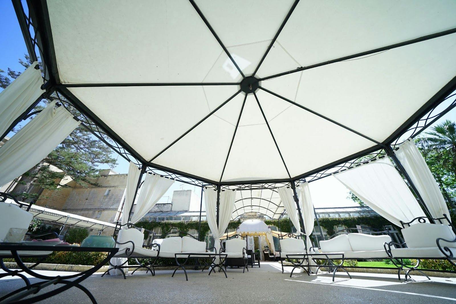 Retractable patio canopy or roof providing adjustable shade over outdoor seating with light curtains and metal framing.