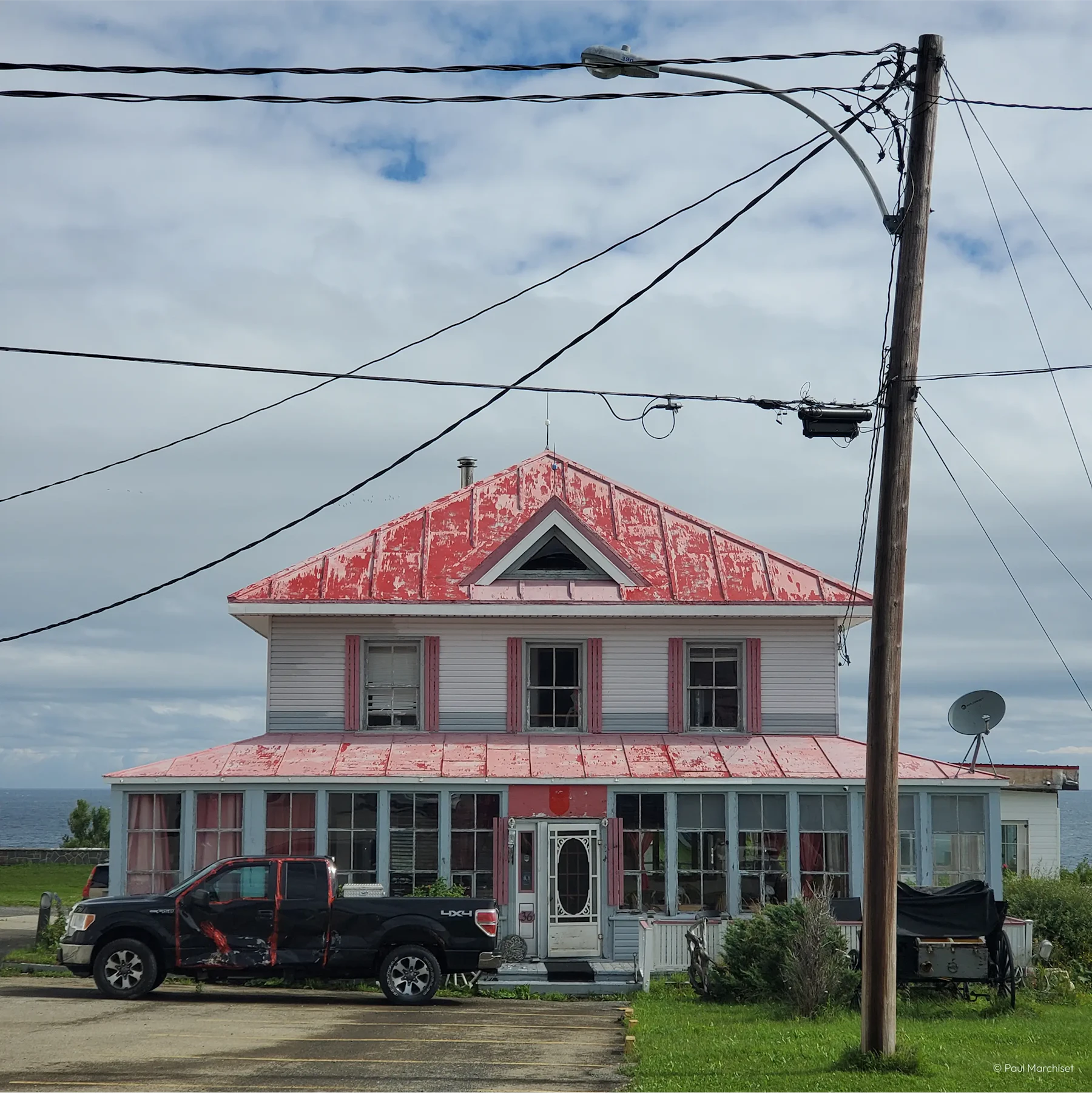 a white house with pink roof in front of a cloudy background