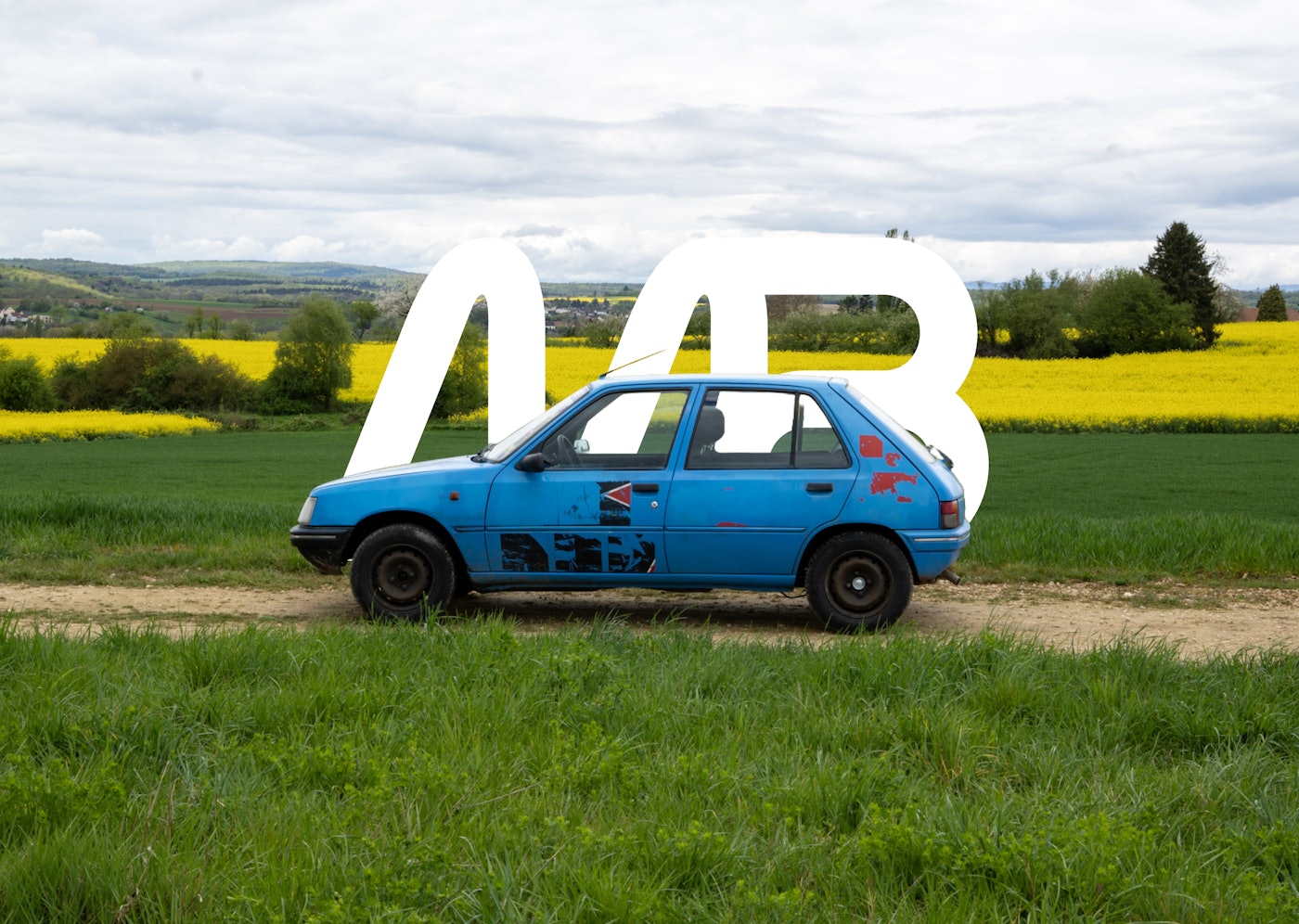 a blue car in front of a rapeseed field with the logo of Motor's Brothers