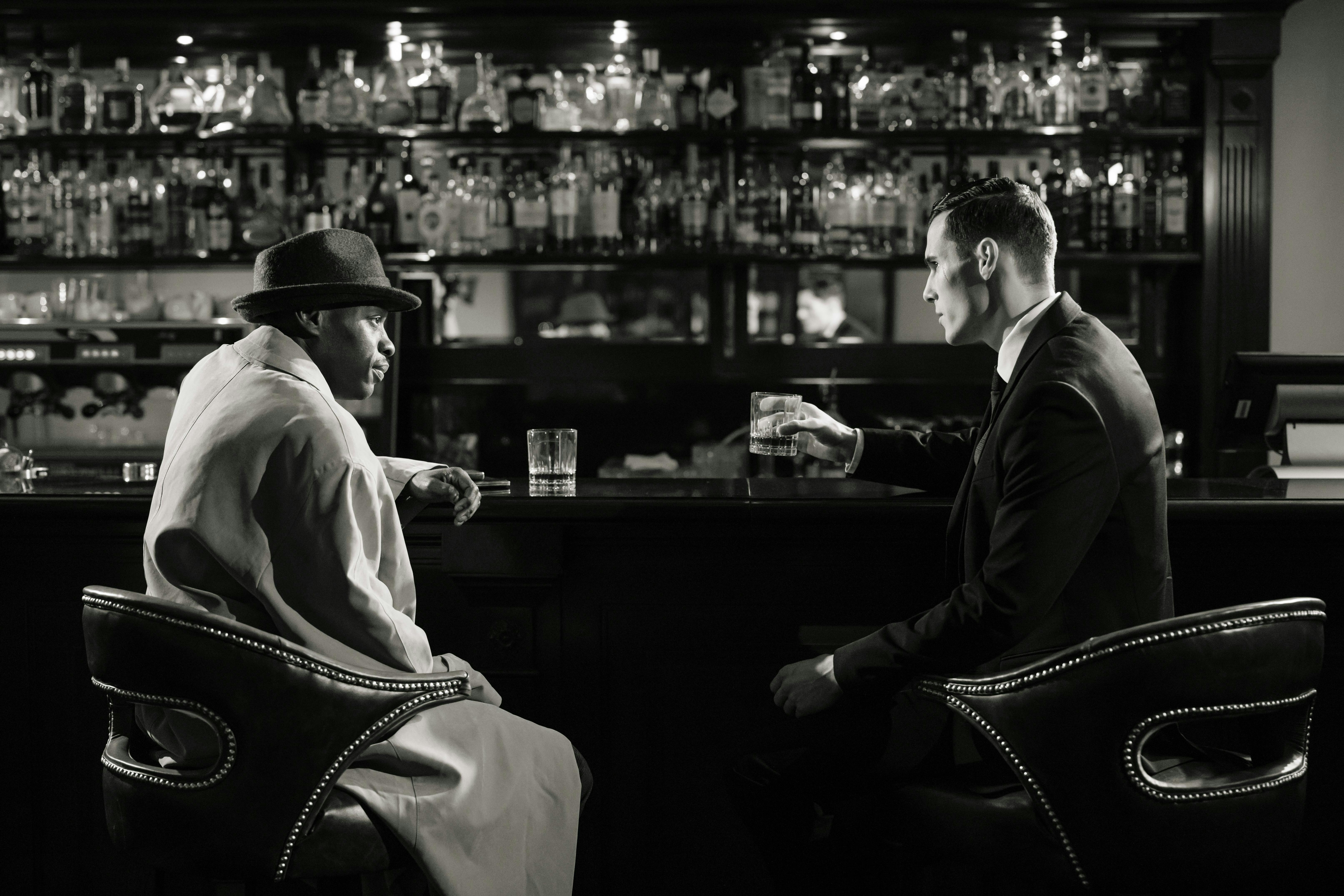 black and white picture of two men talking at a bar