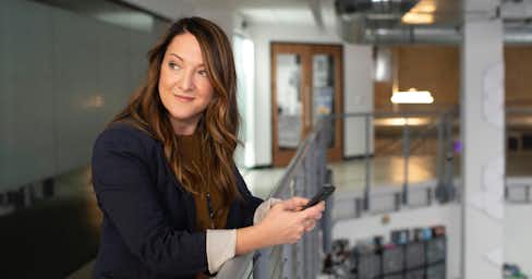 Woman in an office setting holding a phone.