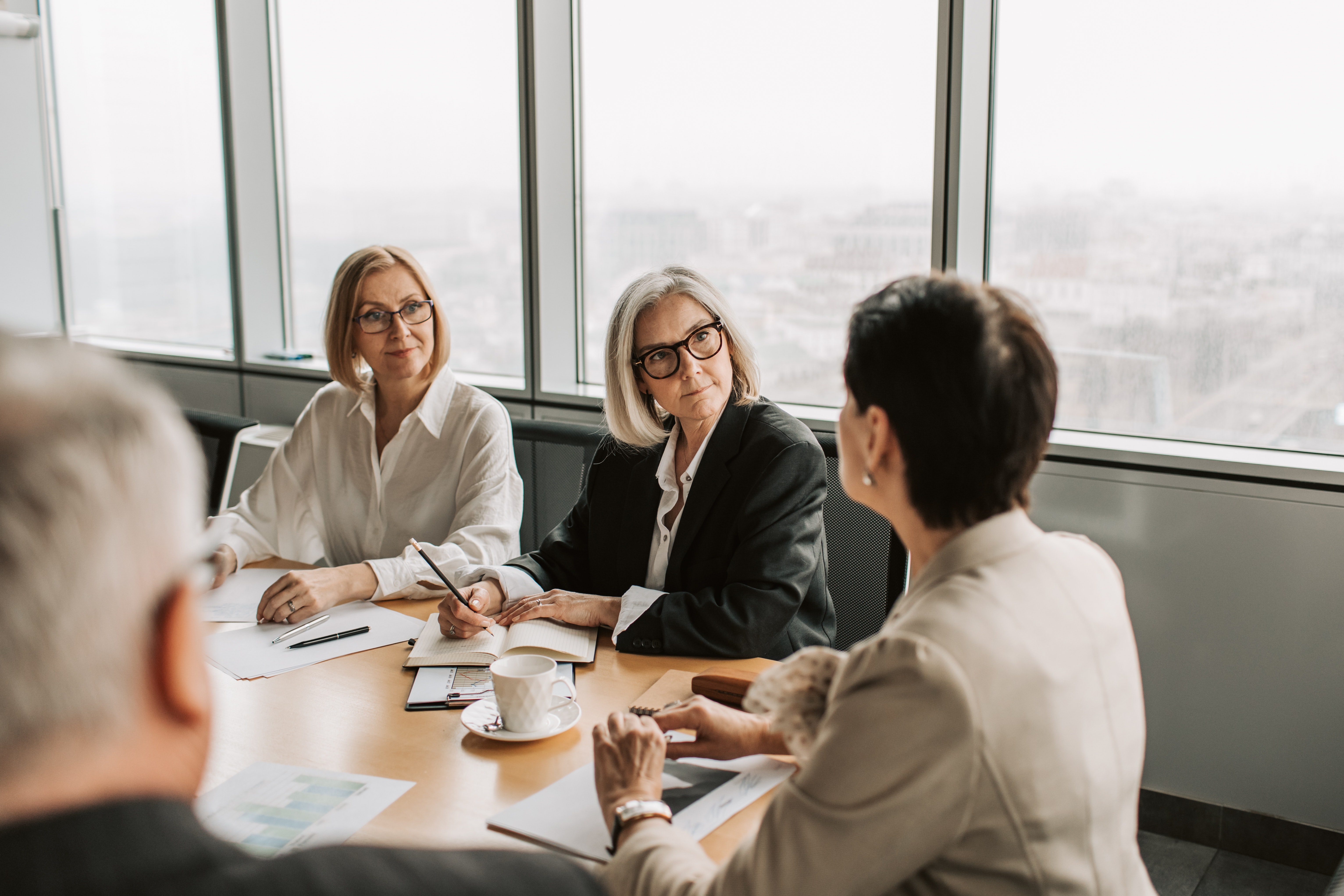 Three women and a man in a conference room in the middle of a work meeting.