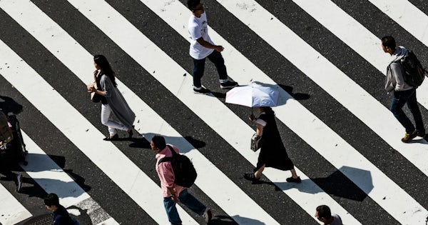 Ein Foto aus der Vogelperspektive von Menschen, die eine Straße überqueren.
