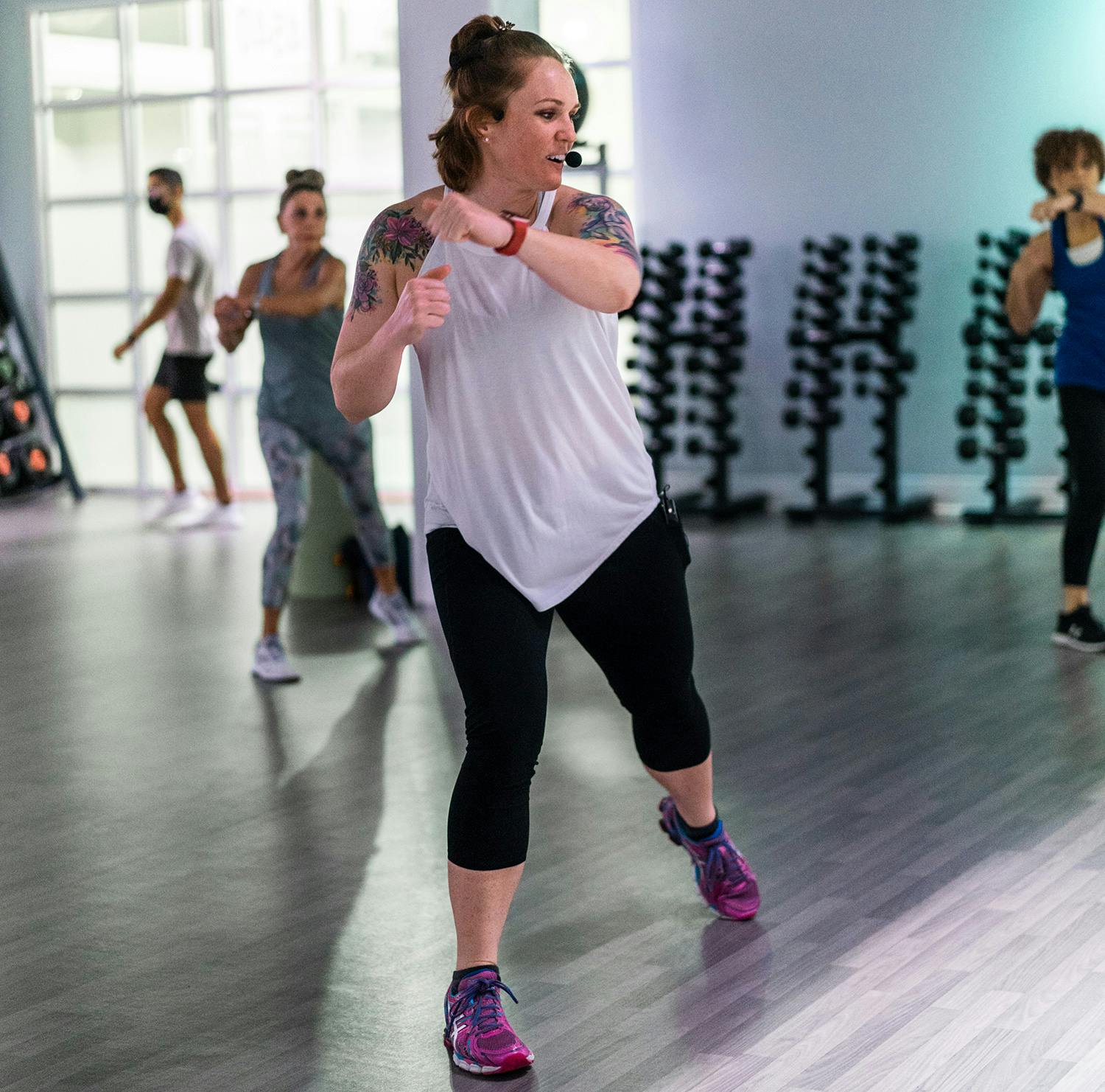 Instructor leading cardio kickboxing class in gym studio