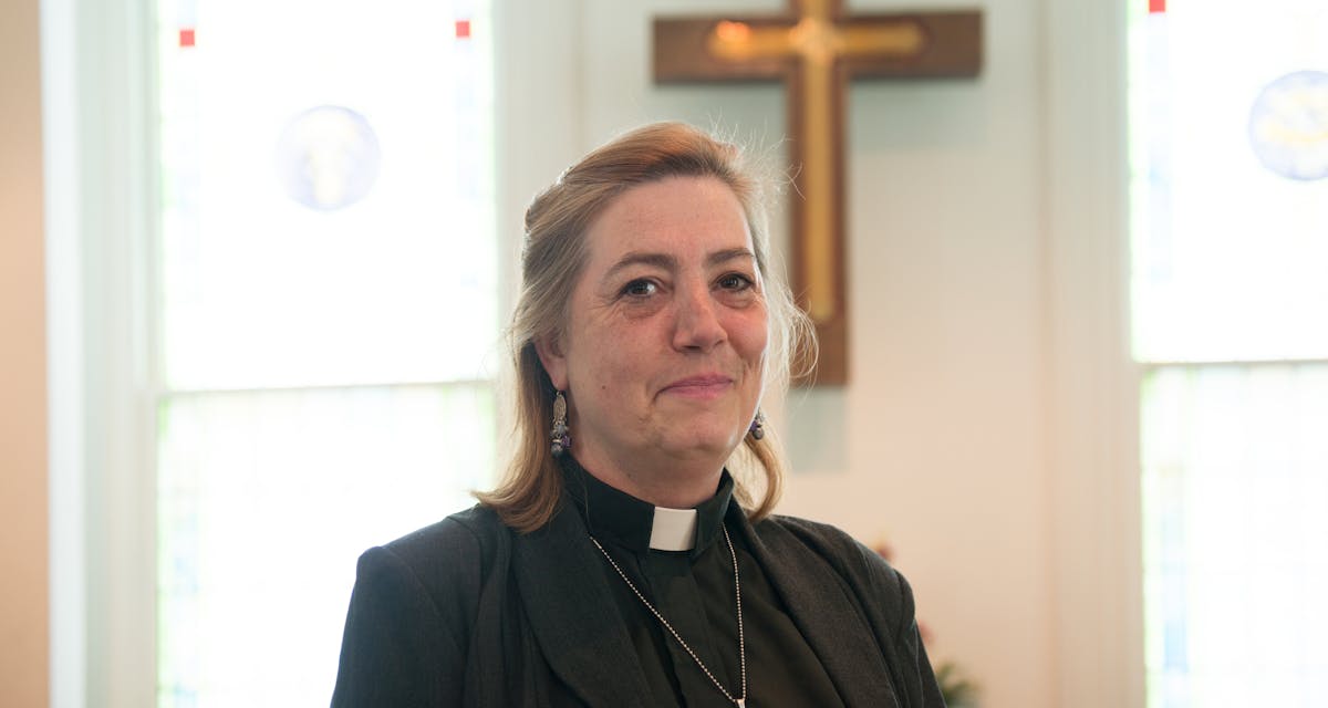 Female pastor inside church with cross in background