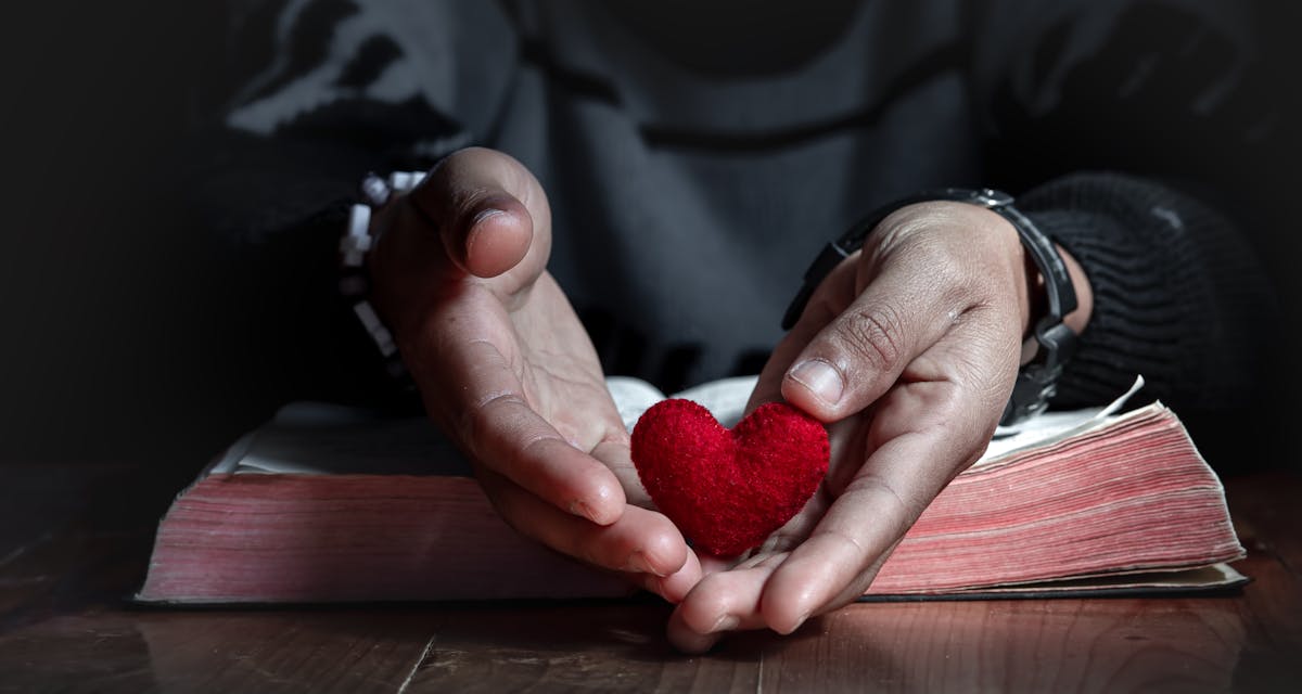 priest holding heart on bible