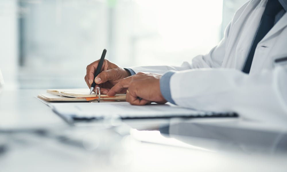 Closeup of doctor's hands writing on paper