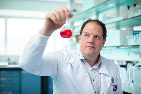 Photo of a researcher holding up a beaker of red liquid