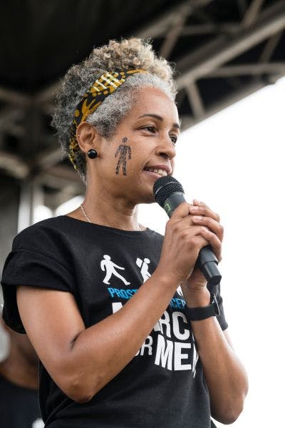 Close-up of Karen speaking into a microphone wearing a Prostate Cancer UK t-shirt