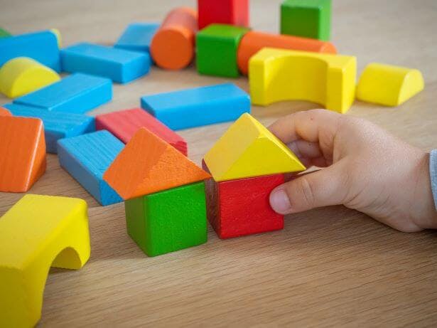 hand playing with colorful wooden blocks of various shapes 