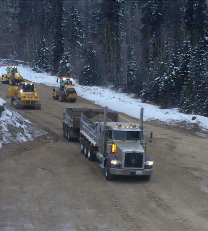 Cats, packers, and gravel trucks building up a road