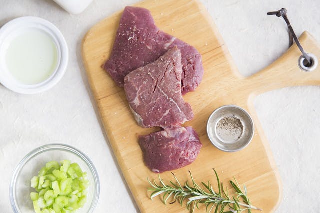 cube steaks on a wood cutting board with fresh rosemary