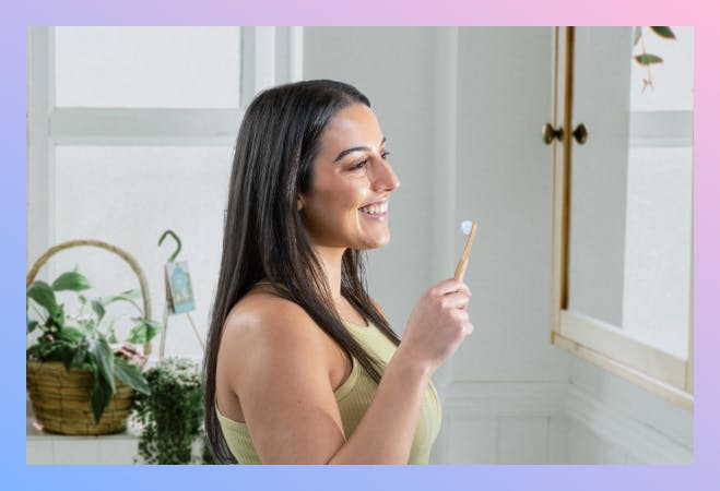 A girl standing in front of a bathroom mirror, brushing her teeth with the Pearlii Mosobrush