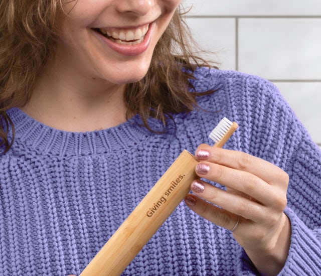 Woman in purple jumper placing her Pearlii Mosobrusgh into her Mosobrush Travel Case