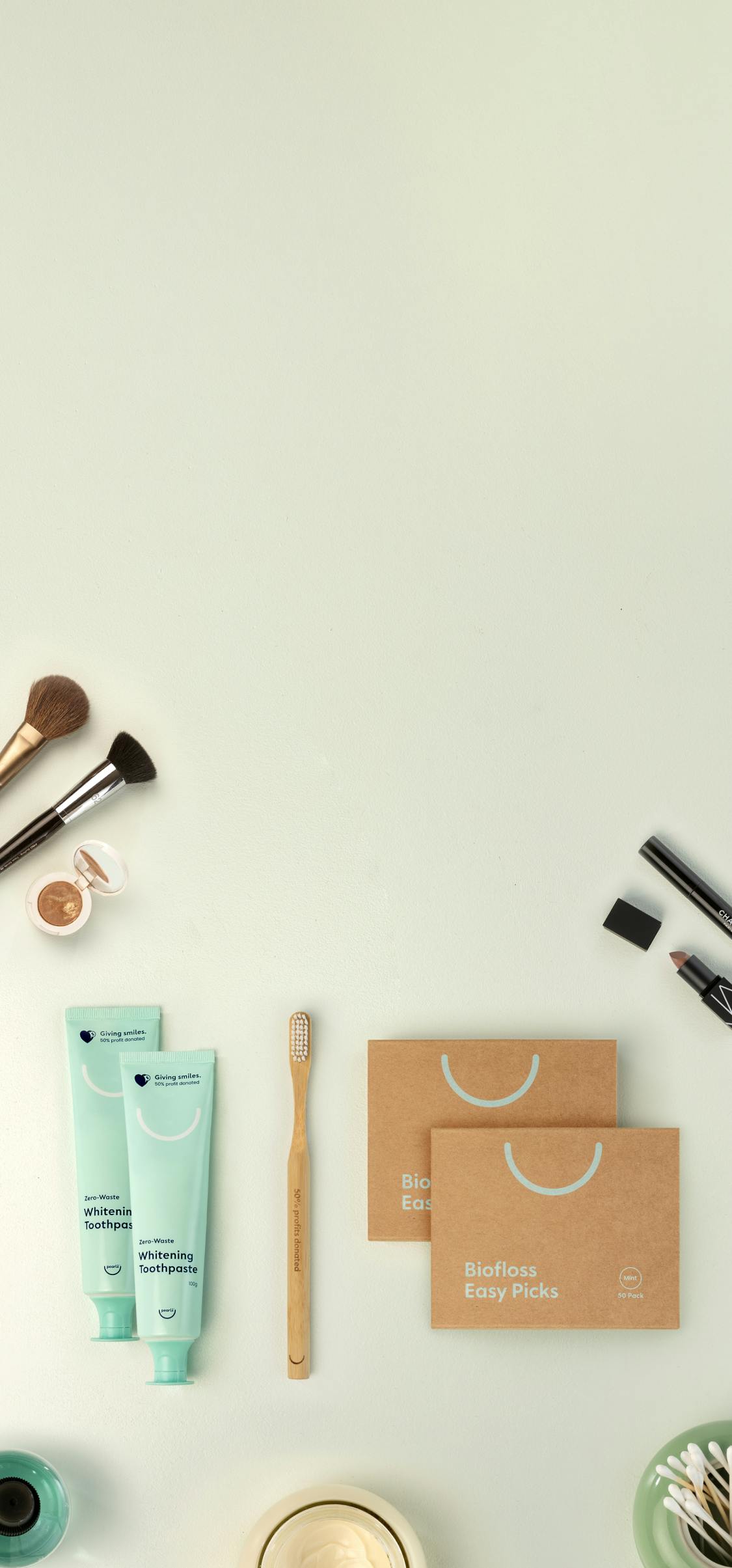 Pearlii products display photo showing 2 x Pearlii Zero-Waste Whitening Toothpaste, 1 x Mosobrush and 2 x Biofloss Easy Picks, along with other bathroom accessories displayed on a benchtop.