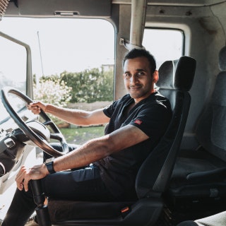 Dentist and founder of The Dental Truck, Dr Jalal Khan, sitting in drivers seat of a dental truck
