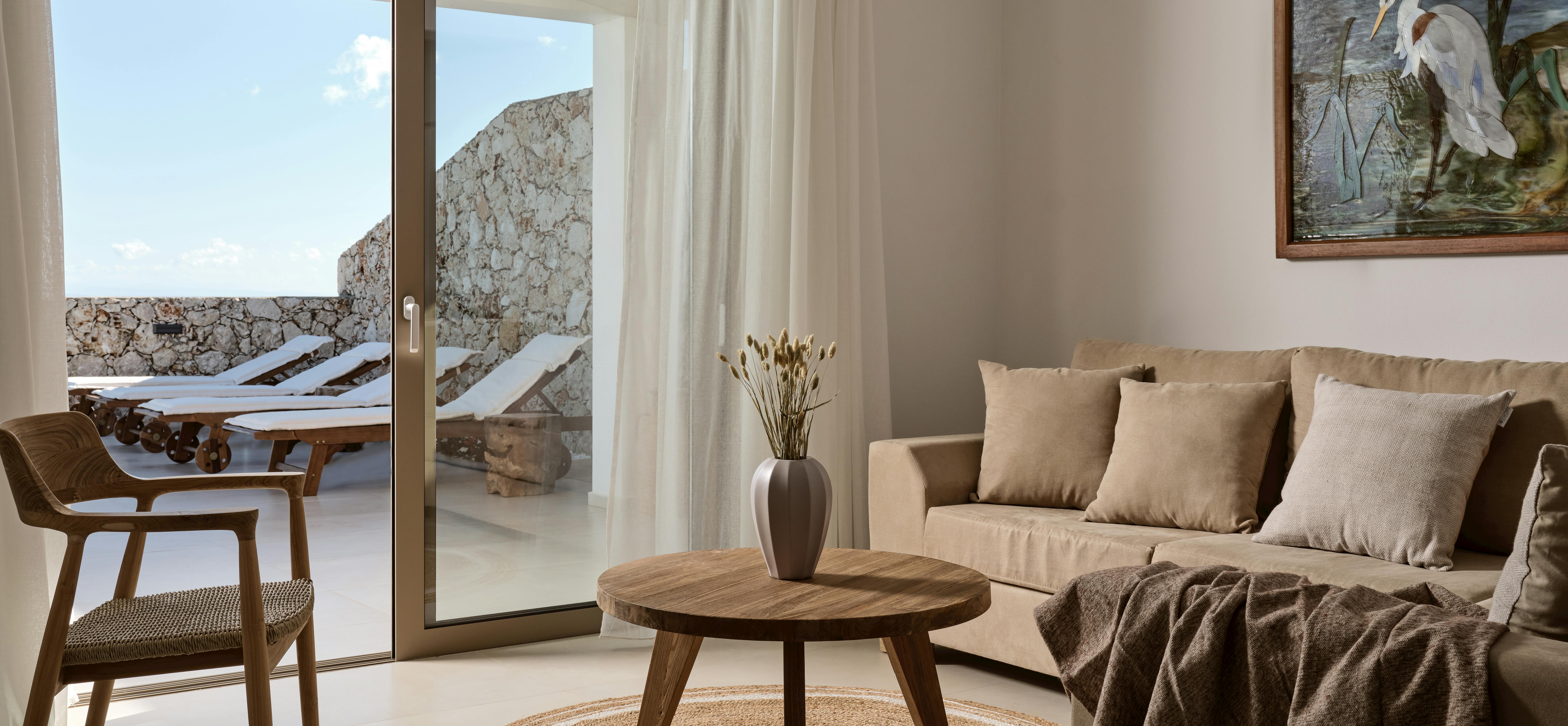 Light-filled living room with terracotta sofa, wood furniture, and terrace views through glass doors.