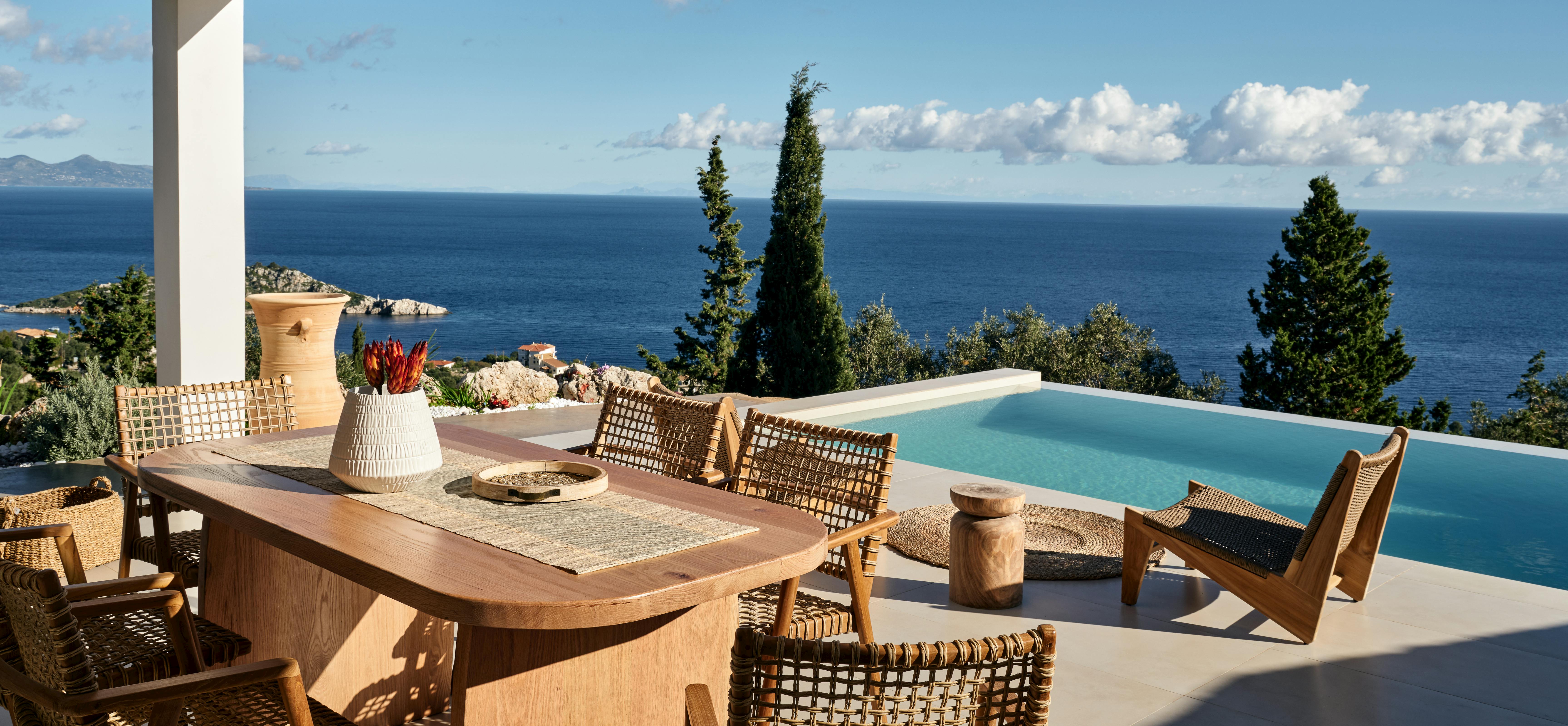Expansive terrace with infinity pool, dining area, and panoramic views of Greek coastline and islands.