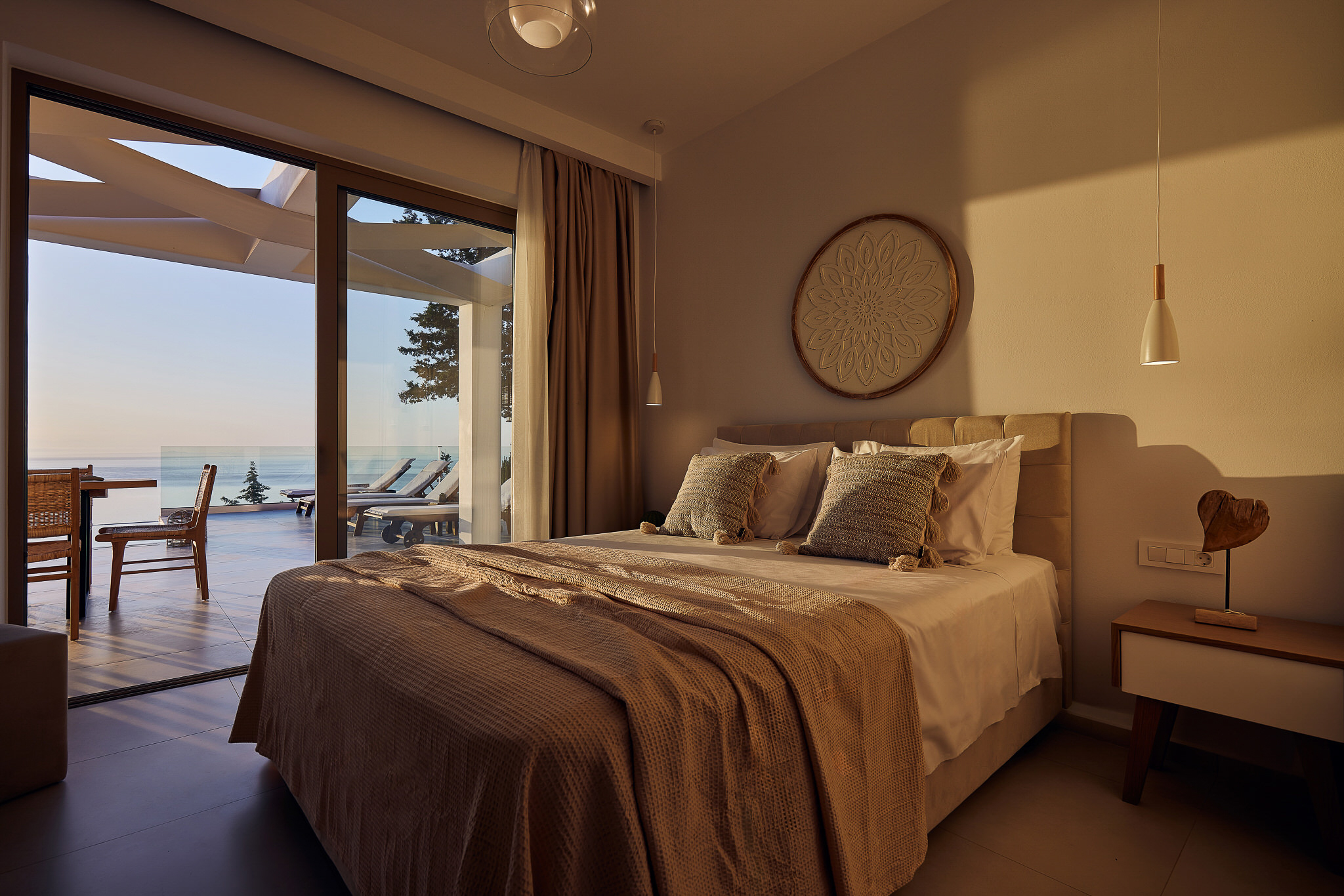 Tan sectional sofa with botanical pillows, paired wood coffee tables, and framed geometric art on wall.