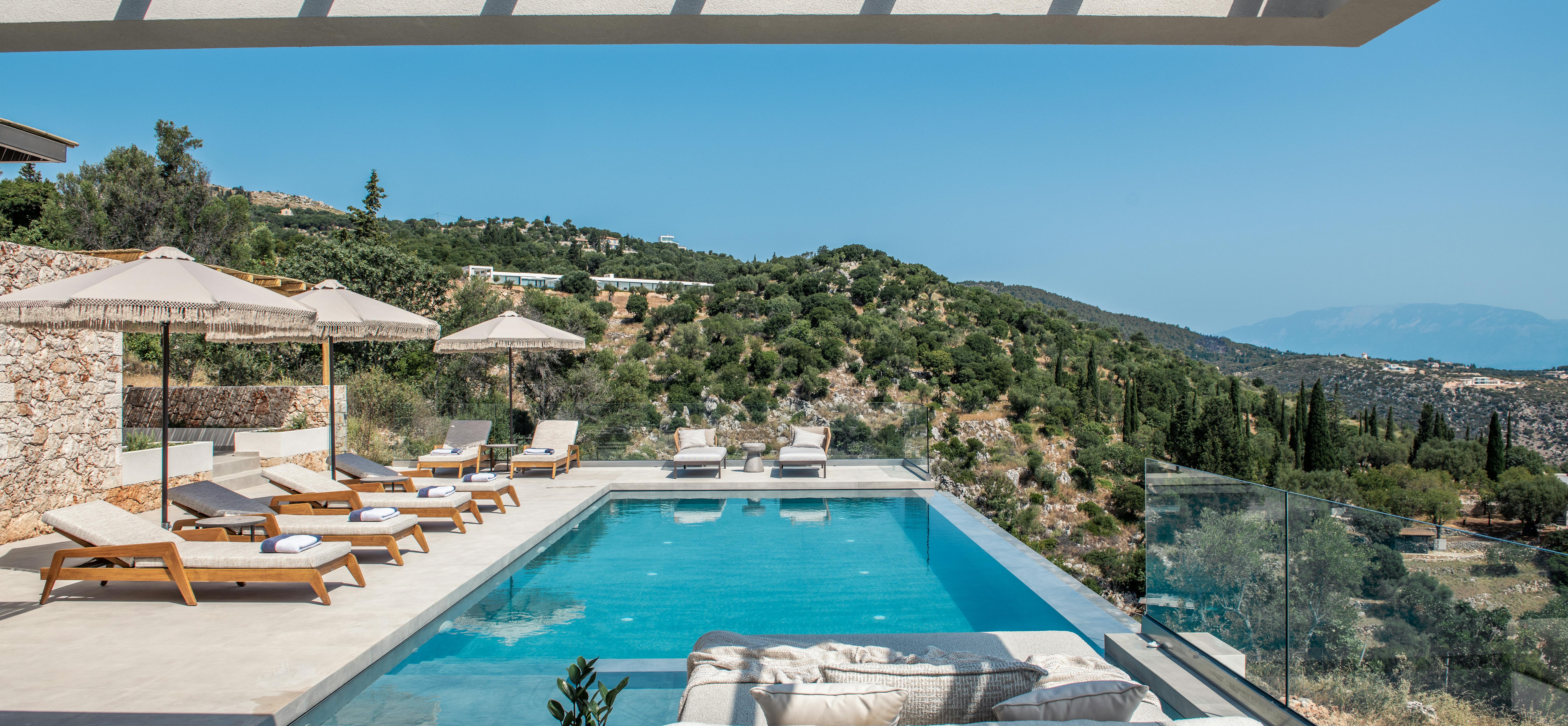 Pool area with modern pergola, grey outdoor sofa, and panoramic hillside landscape views.