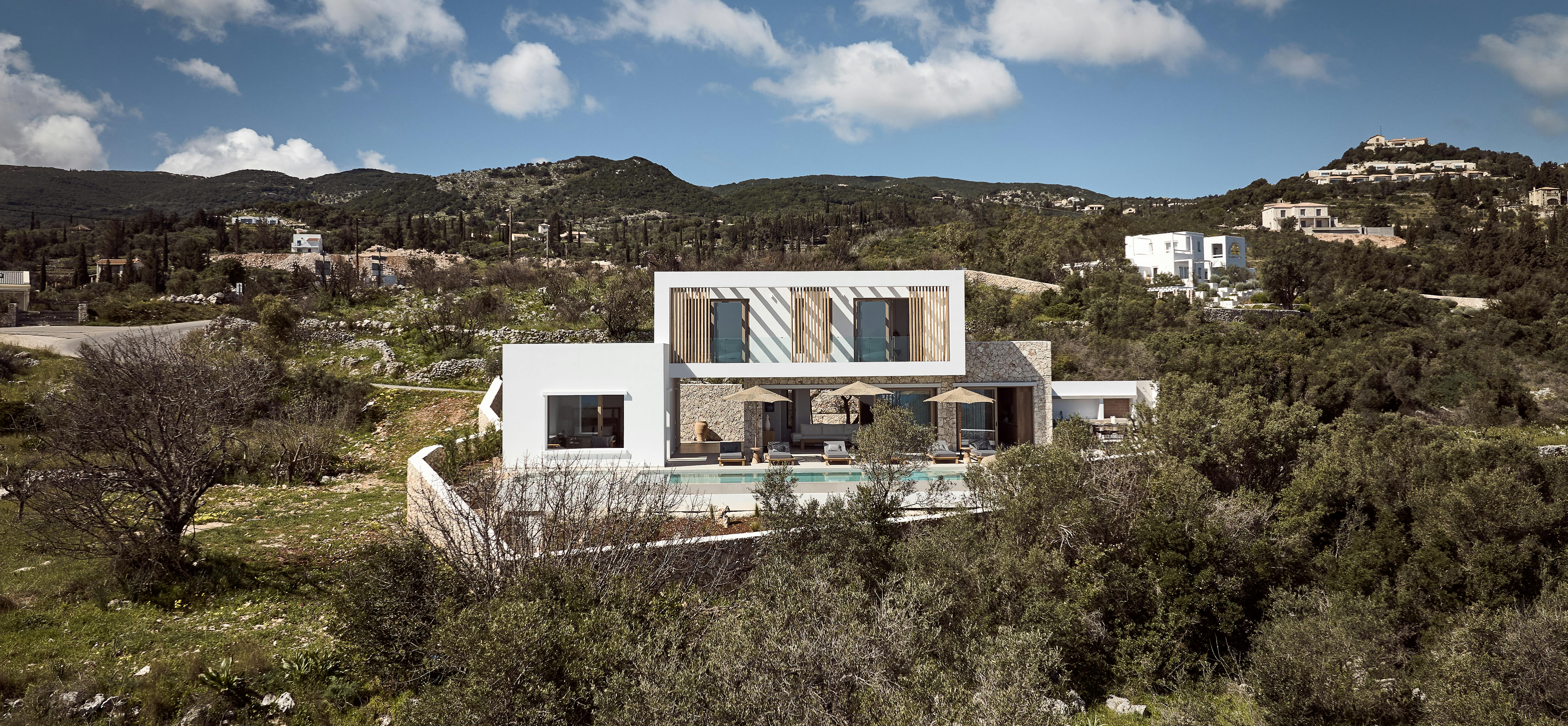 Contemporary villa nestled in natural landscape with stone walls, infinity pool, and wooden screening details.