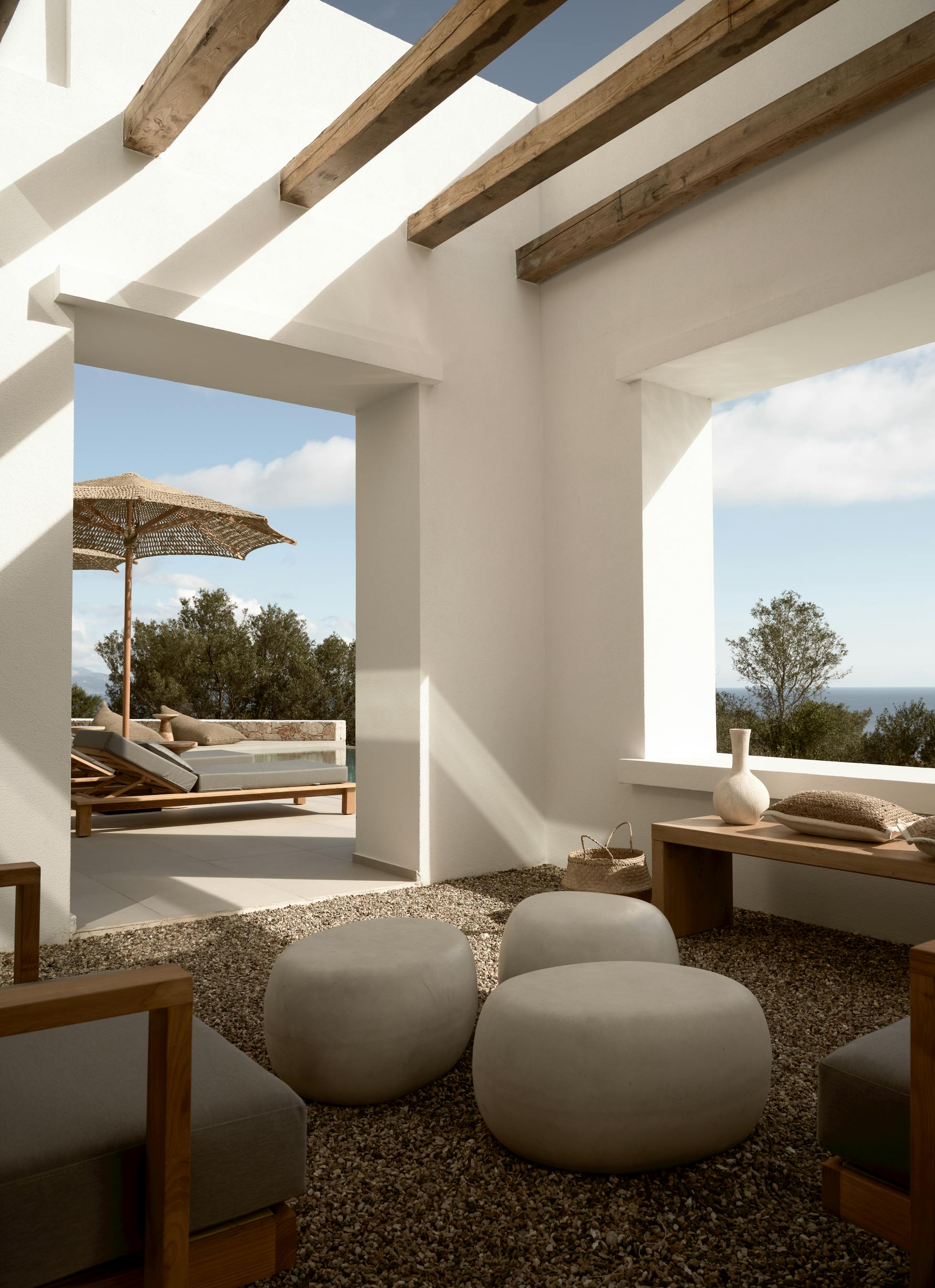 Zen-style covered terrace with exposed wooden beams, stone floor seating, and Mediterranean landscape views.