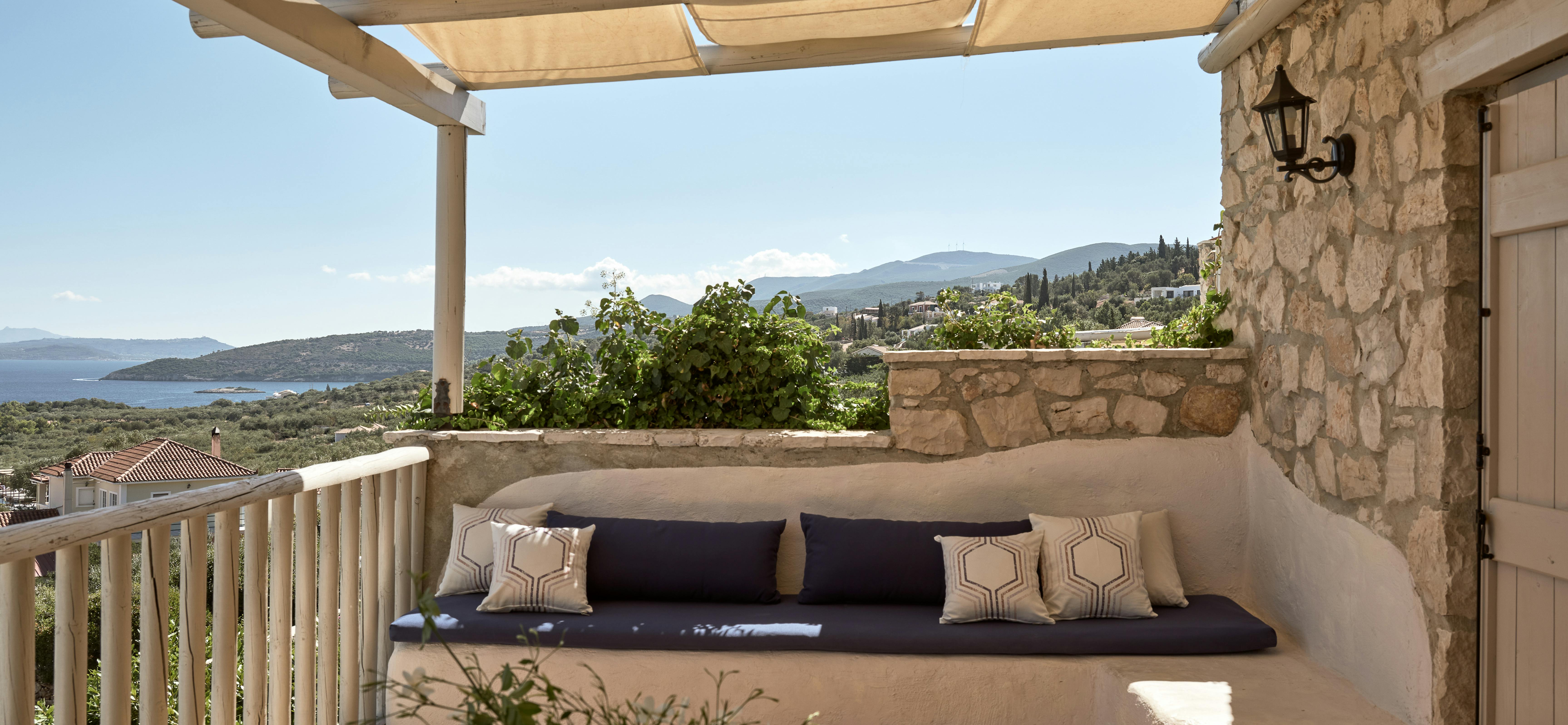Covered terrace seating area with built-in bench and coastal mountain views.