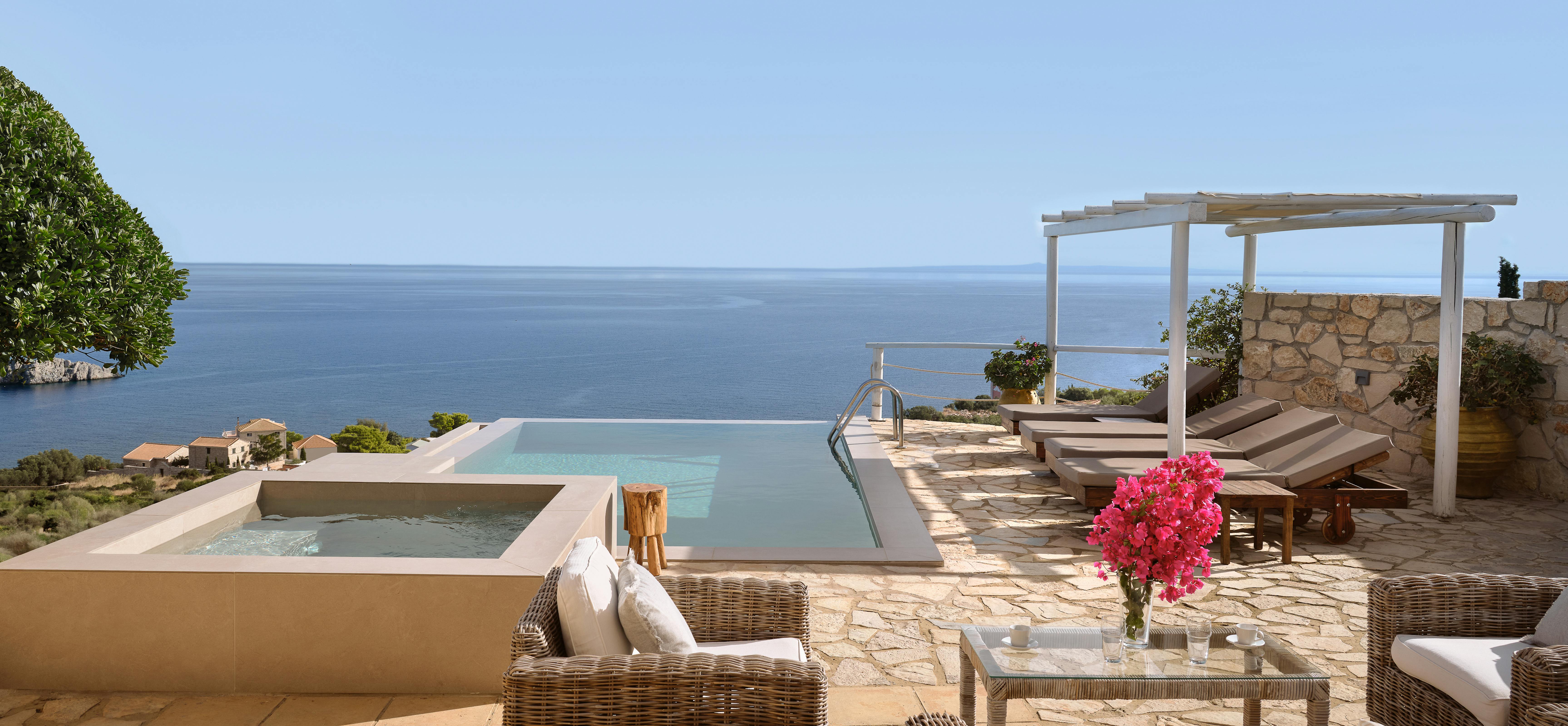Luxury infinity pool terrace with wicker lounge furniture, hot tub, and panoramic Mediterranean Sea views.