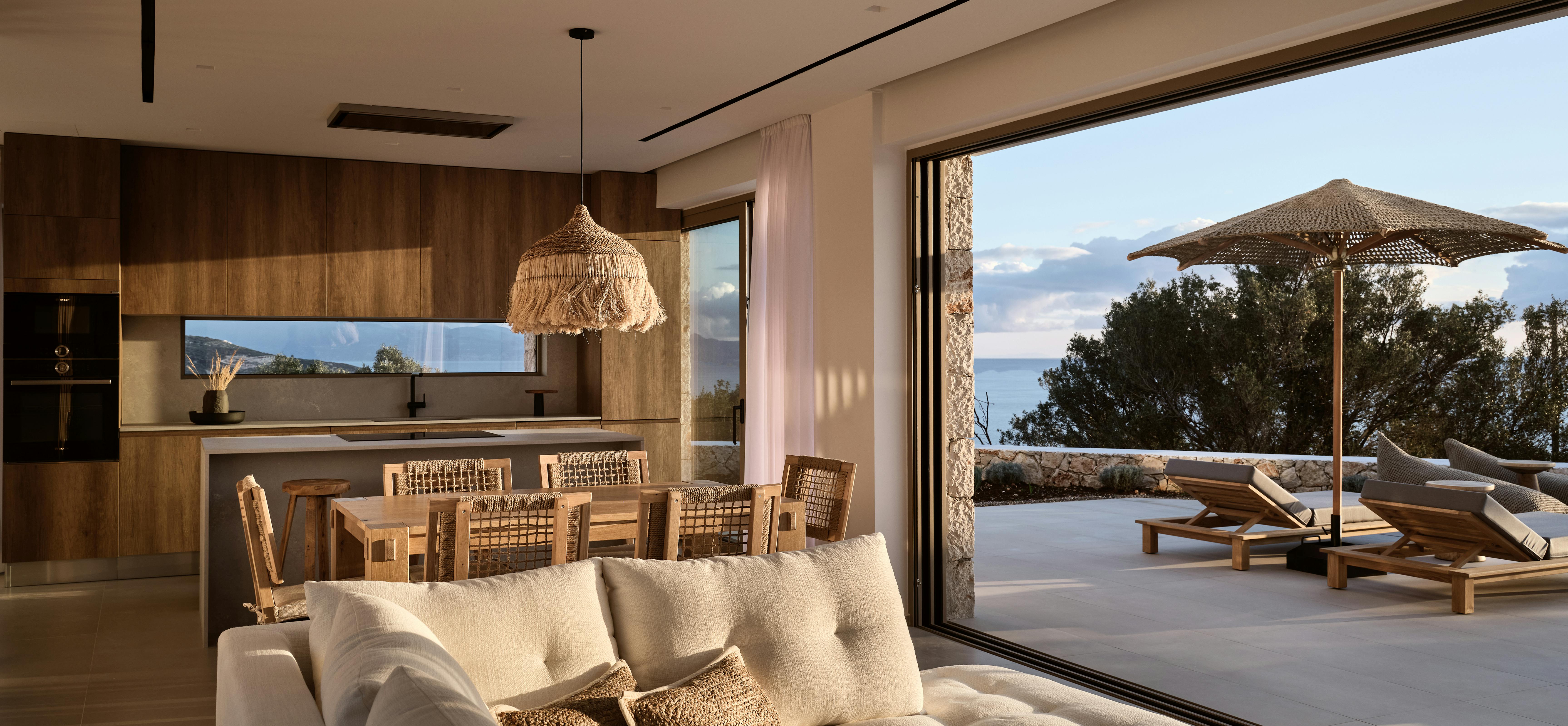 Open living area with cream sectional, woven pendant light, and seamless indoor-outdoor connection.