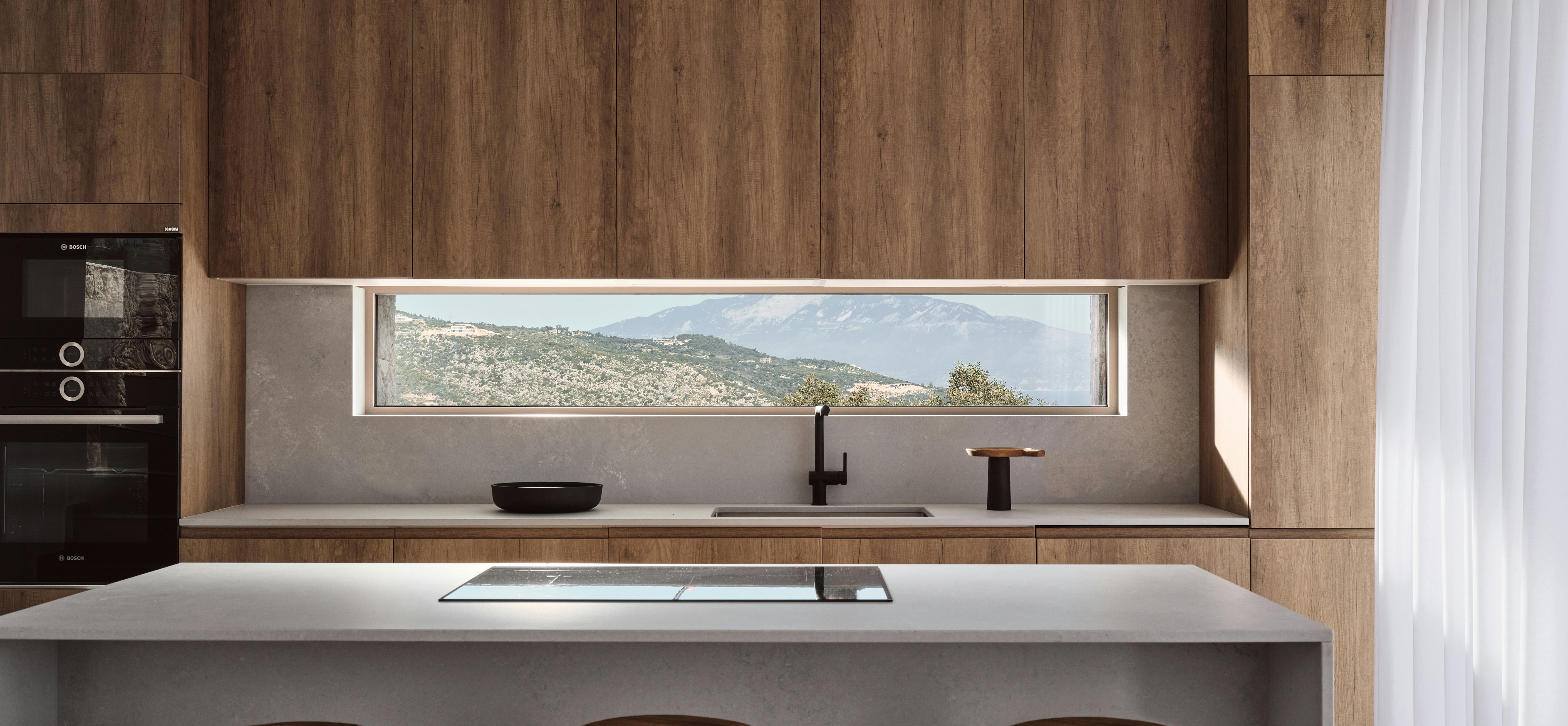 Contemporary kitchen with walnut cabinetry, concrete island, rustic wooden stools, and panoramic window.