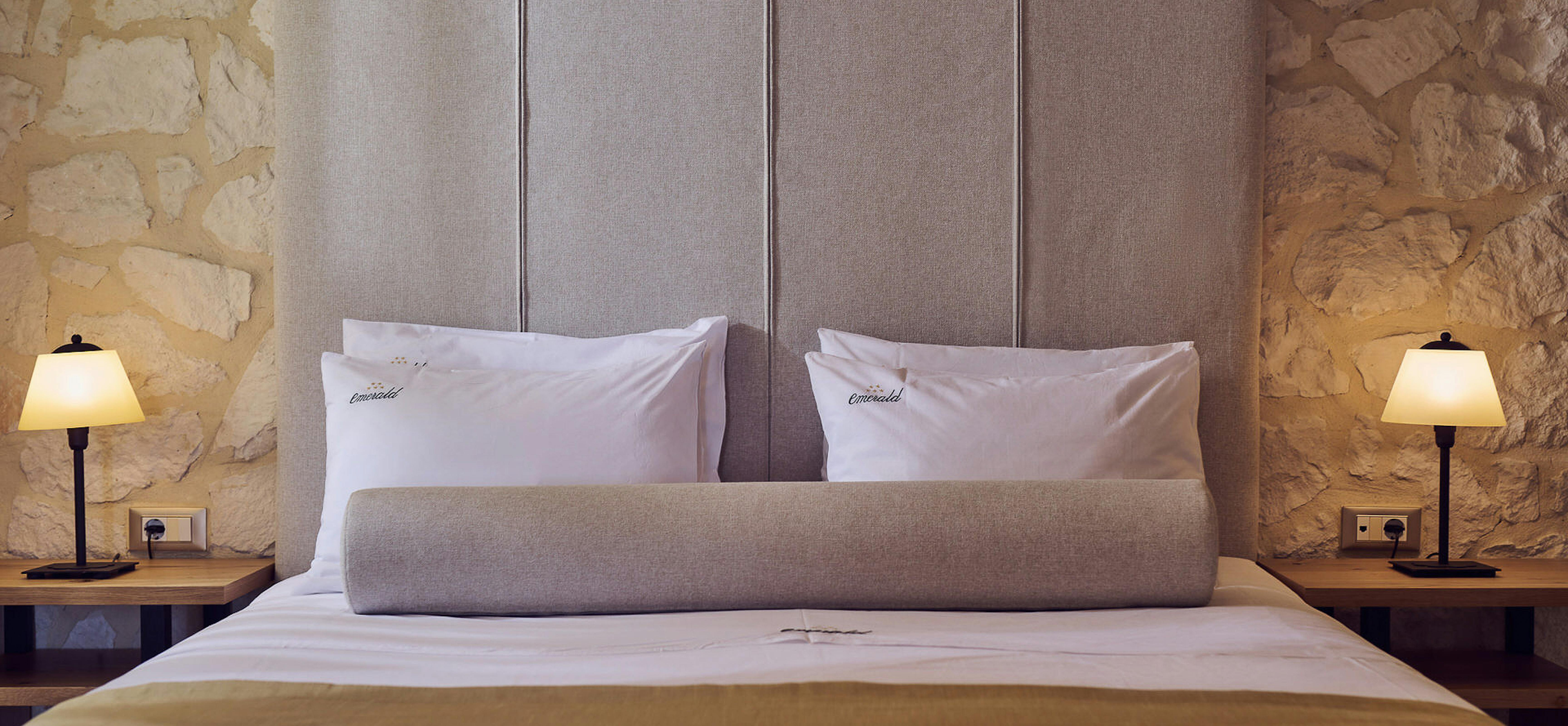 Elegant master bedroom with grey upholstered headboard and stone wall backdrop.