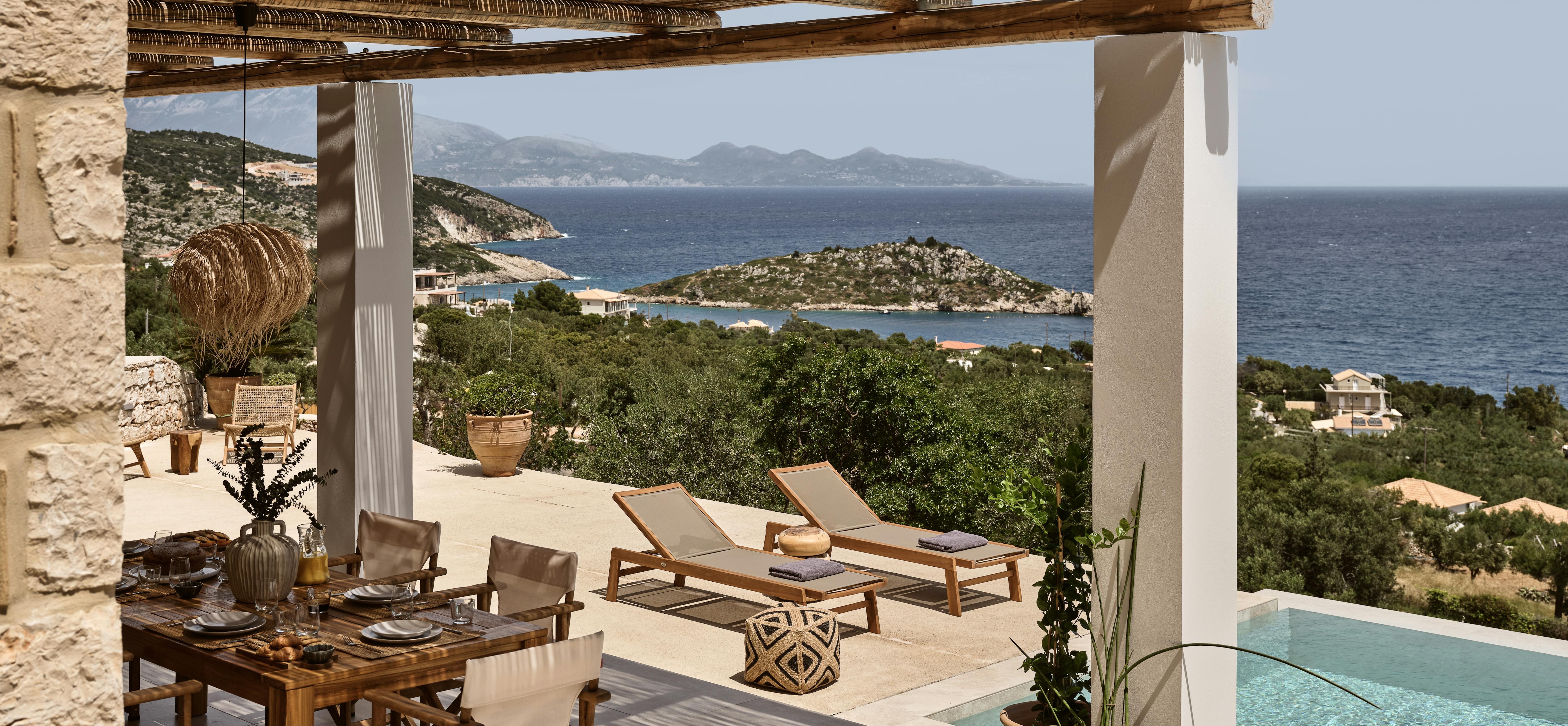 Covered terrace with reed ceiling and white columns, featuring dining area and loungers overlooking the Mediterranean Sea.
