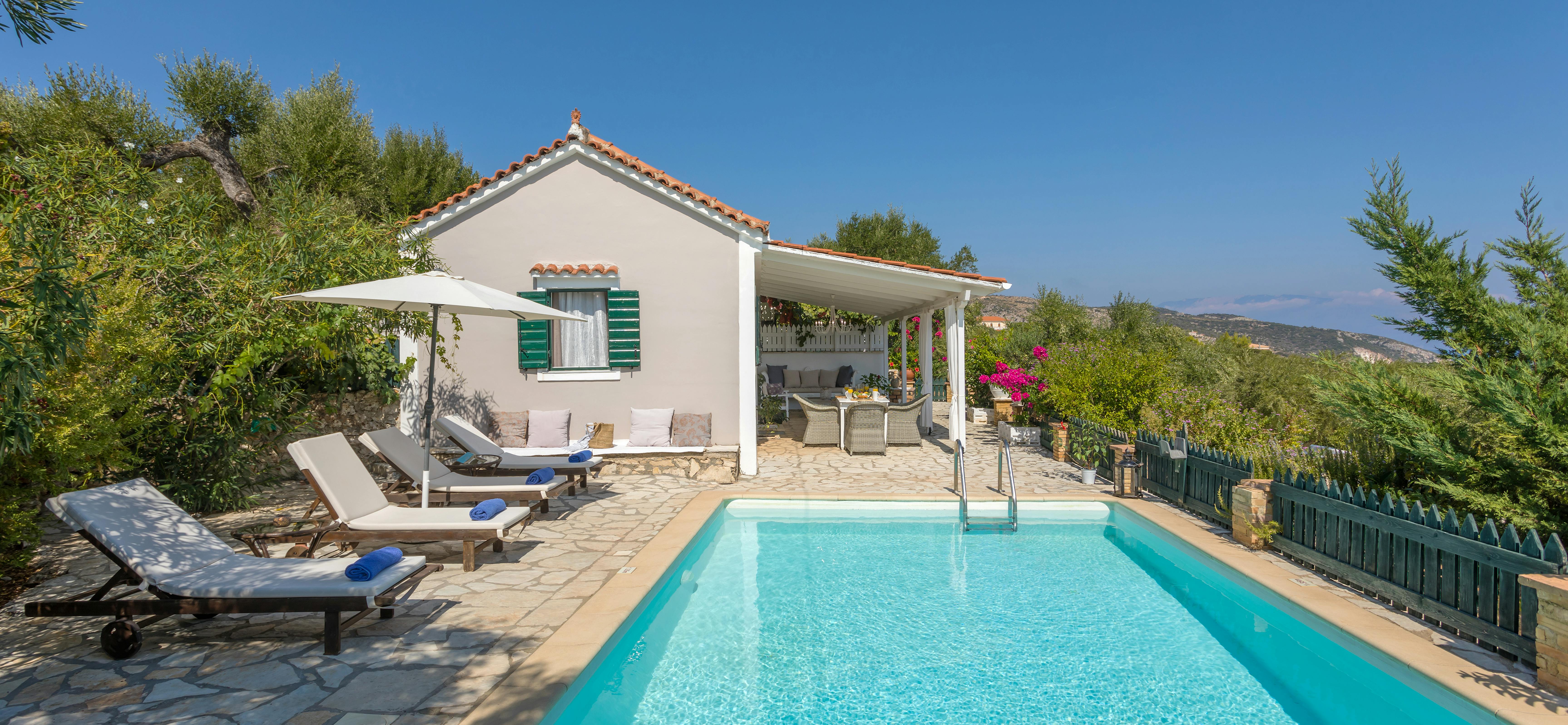Mediterranean villa with terracotta roof, swimming pool, sun loungers, and hillside sea views.