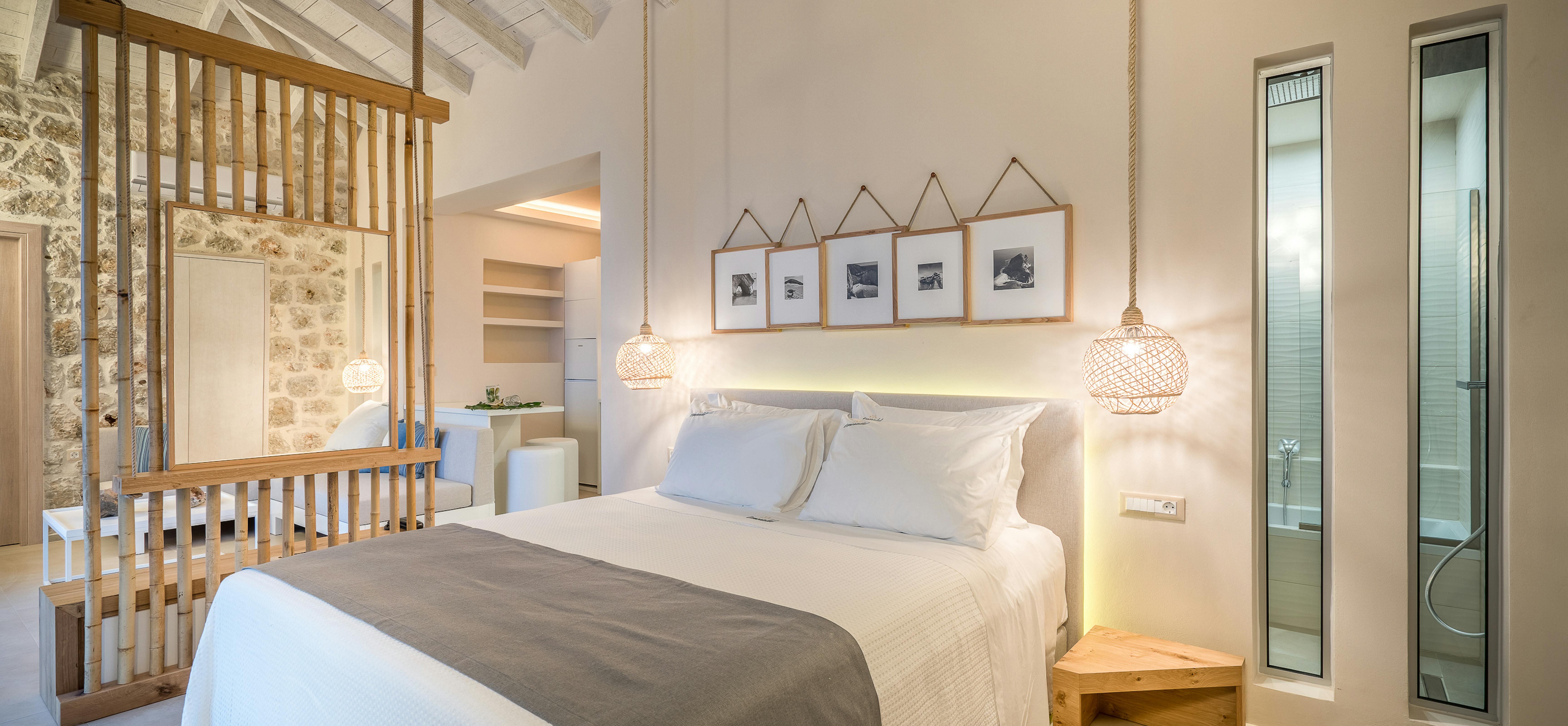Minimalist bedroom with white bedding, grey runner, wooden floating shelves, woven pendant lights, framed photos, and vaulted ceiling.